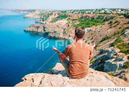 Tourist man outdoor on edge of cliff seashore Tourist man outdoor on edge of cliff seashore 71241745