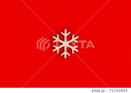 Flat natural unpainted wooden snowflake shape on red background. 71242695