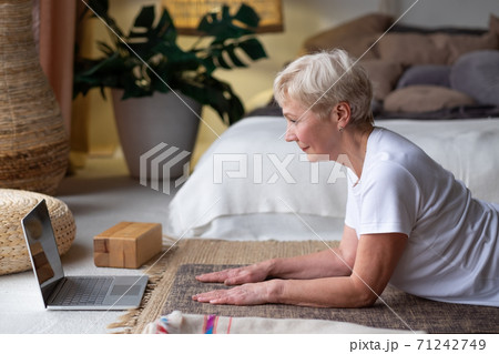 Active senior woman surfing in internet on yoga mat. Active senior woman surfing in internet on yoga mat. 71242749