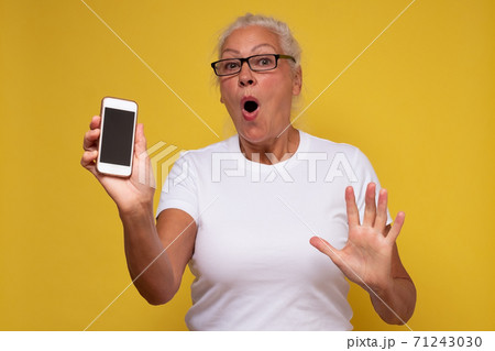 Mature caucasian mom wear glasses extend arm hold smartphone show phone screen Mature caucasian mom wear glasses extend arm hold smartphone show phone screen 71243030