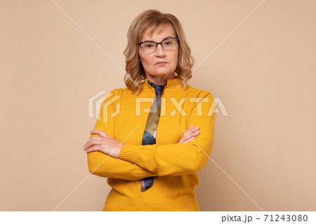 Serious caucasian woman in glasses standing with folded hands and looking at camera Serious caucasian woman in glasses standing with folded hands and looking at camera 71243080
