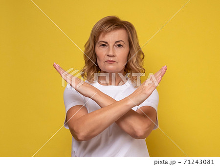 Mature woman making X sign with crossed hands, gesturing stop, warning of danger. 71243081