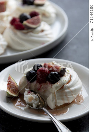 Mini Pavlova meringue cakes decorated with berries and figs. Mini Pavlova meringue cakes decorated with berries and figs. 71244100
