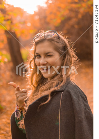 A beautiful young girl in a black cloak is wearing chameleon glasses in autumn. Yellow forest, green grass, blonde. webinar activity concept 71245194