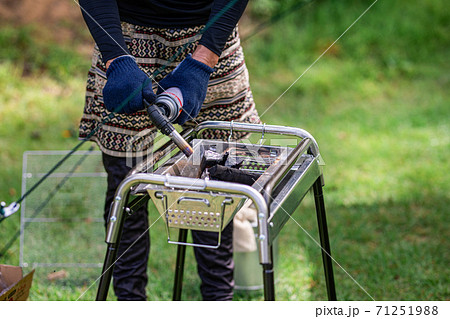 キャンプで炭に火を付けるアジア人男性 71251988