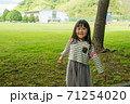 芝生の前に立つ笑顔の女の子 71254020