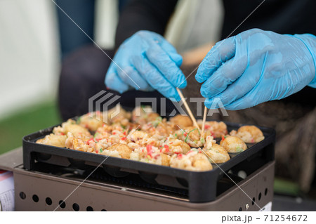 キャンプ場でたこ焼きを焼く男性 71254672