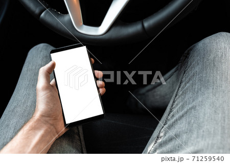 Interior view of a modern new car. Young driver using smartphon in the car while driving or parking. Mockup of a mobile phone with isolated white screen in the hands of a woman. 71259540