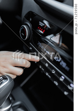Interior view of a new car. Climate or air conditioner system adjusted by a woman. Adjusting temperature of car's interior 71259560