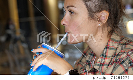 Young woman enjoying a drink with the straw. Drinking cola or soda pop with a straw. Close up portrait shot. 71261572