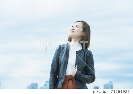 屋外で笑顔を見せるオフィスカジュアルスタイルの女性 71261927