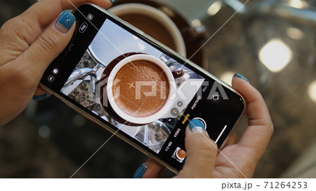 Close up of woman holds modern smartphone and taking pictures of cocoa to share photos on social media resources Close up of woman holds modern smartphone and taking pictures of cocoa to share photos on social media resources 71264253