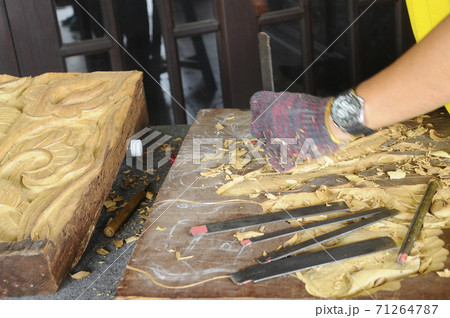 PUTRAJAYA, MALAYSIA - DECEMBER 07,2017: A man is carving wood using traditional hand tools. Carvings based on flora motifs 71264787