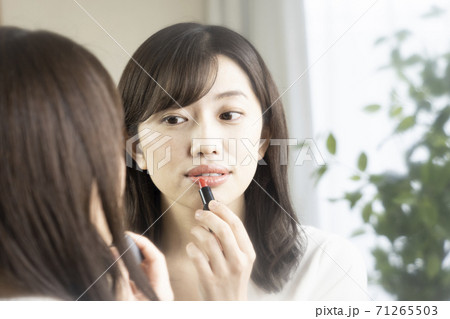 鏡を見ながら口紅を塗る女性 71265503