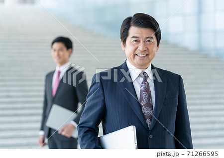 ビジネス 企業のロビーに立つ若い男性とミドルエイジの笑顔の男性 ビジネス 企業のロビーに立つ若い男性とミドルエイジの笑顔の男性 71266595
