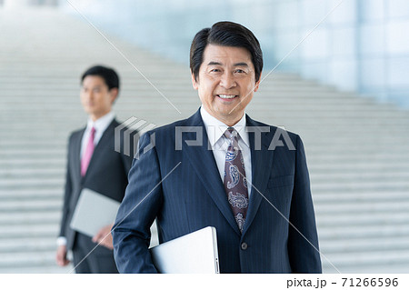 ビジネス 企業のロビーに立つ若い男性とミドルエイジの笑顔の男性 ビジネス 企業のロビーに立つ若い男性とミドルエイジの笑顔の男性 71266596