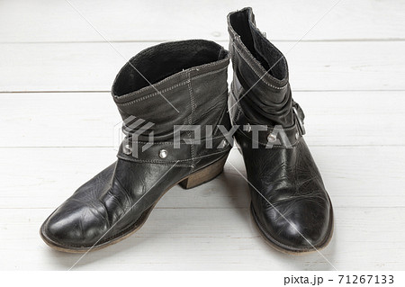 Women cowboy boot. Black leather shoes on a white wooden table. Composition of clothes. Flatlay. 71267133