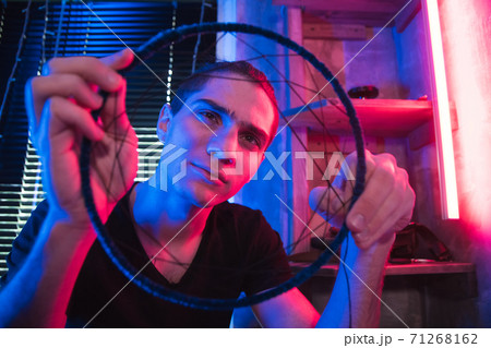 Artisan looks at dreamcatcher in futuristic workshop. 71268162