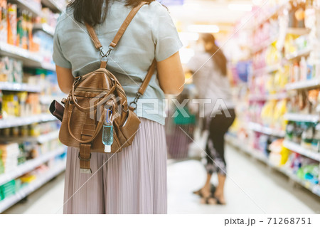 Mini portable alcohol gel bottle to kill Corona Virus(Covid-19) hang on a leather shoulder bag of a woman wearing a mask to shopping in supermarket.New normal lifestyle.Selective focus on alcohol gel Mini portable alcohol gel bottle to kill Corona Virus(Covid-19) hang on a leather shoulder bag of a woman wearing a mask to shopping in supermarket.New normal lifestyle.Selective focus on alcohol gel 71268751