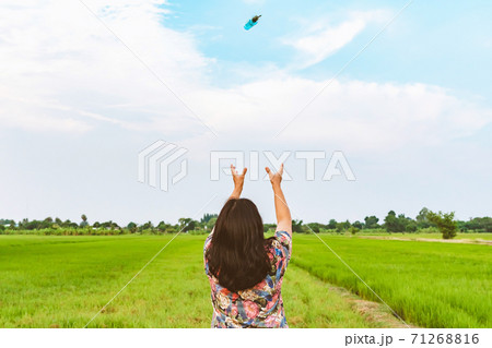 Back view of woman raises her arms to wait for alcohol gel bottle falling from the sky in the rice field.Campaign to prevent the spread of the Corona virus(Covid-19).New normal concept.Selective focus 71268816