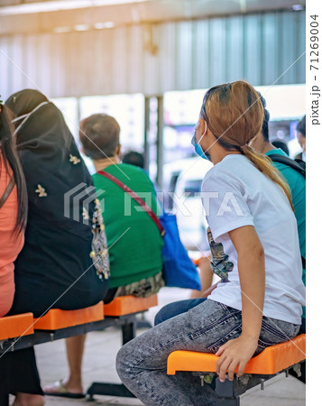 Back view of female travelers wear protective face mask to prevent Corona Virus(COVID-19) sitting and waiting for the van at transport station.New normal lifestyle, Epidemic situation,Selective focus Back view of female travelers wear protective face mask to prevent Corona Virus(COVID-19) sitting and waiting for the van at transport station.New normal lifestyle, Epidemic situation,Selective focus 71269004