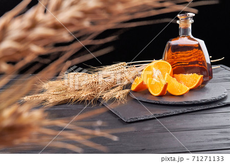 Close-up ears of wheat and cognac with orange slices. 71271133