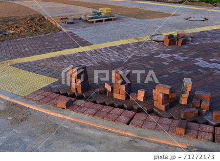 Process of installing paving bricks in the town pedestrian zone. Laying paving slabs and borders at construction site.  71272173