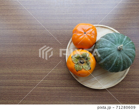 秋の味覚・皿に置かれた2つの柿とカボチャ 71280609