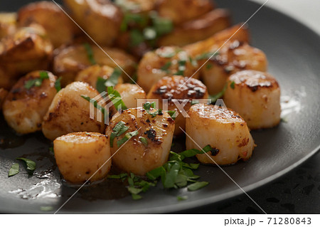 roasted scallops with baked potatoes wedges on a black plate roasted scallops with baked potatoes wedges on a black plate 71280843