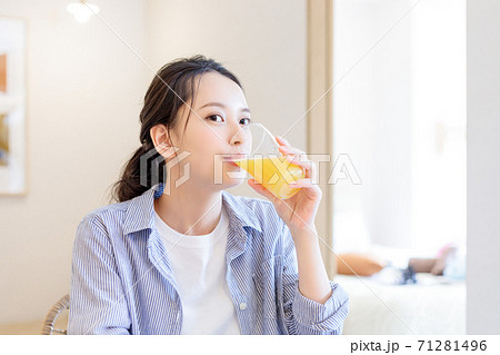 自宅でオレンジジュースを飲む若い女性 71281496