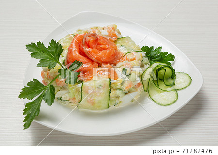 salad of boiled vegetables, with salmon, decorated with greens and slices of fresh cucumber, on a white plate salad of boiled vegetables, with salmon, decorated with greens and slices of fresh cucumber, on a white plate 71282476