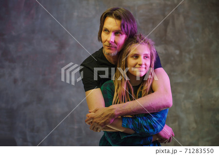 Man and young woman with colorful light posing on dark background. 71283550