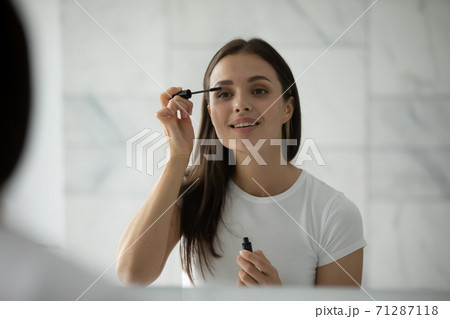 Inspired millennial female making herself up putting mascara on lashes Inspired millennial female making herself up putting mascara on lashes 71287118