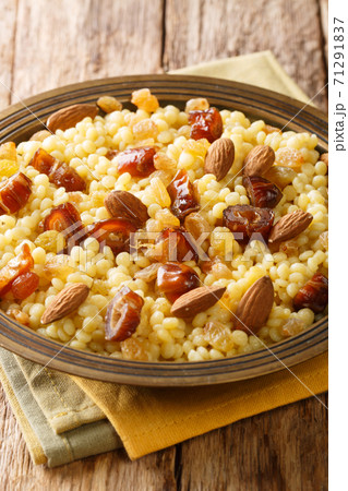 Mesfouf is a steamed Couscous with olive oil, butter, nuts and raisins close-up in a plate. vertical 71291837