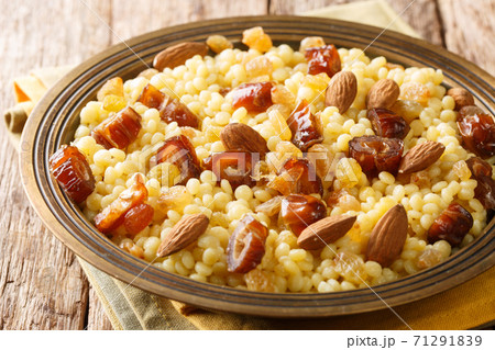 Sweet couscous with almonds, raisins and dates close-up in a plate on the table. horizontal Sweet couscous with almonds, raisins and dates close-up in a plate on the table. horizontal 71291839