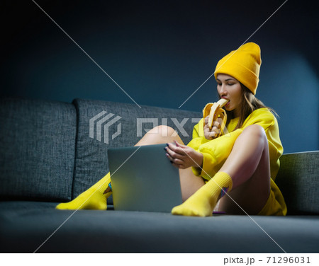 woman on sofa with laptop eating sexy banana 71296031