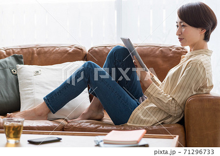 ソファに座りタブレットで動画を見ながら休憩するミドルの女性 71296733