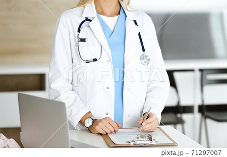 Unknown woman-doctor at work in clinic. Female physician controls medication history record and medical exam results, close-up. Medicine concept 71297007