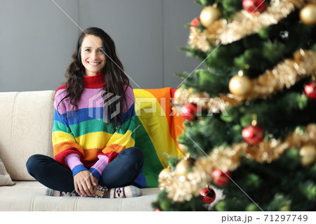 Young beautiful lesbian woman smiling and siting on couch near christmas tree 71297749