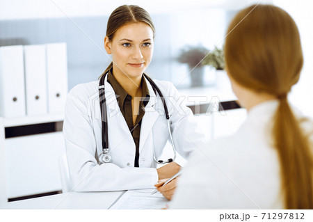 Woman-doctor and patient sitting and talking at hospital office. Green color blouse suits to therapist Woman-doctor and patient sitting and talking at hospital office. Green color blouse suits to therapist 71297812