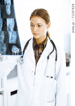 Woman-doctor examining x-ray picture in hospital. Surgeon or orthopedist at work in clinic 71297836