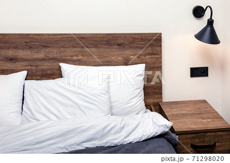 Modern minimalist bedroom interior. Bed with wooden headboard white pillows 71298020