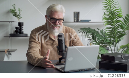 Elderly man with a gray beard video blogger speaking in microphone. Aged broadcaster lives in a studio Elderly man with a gray beard video blogger speaking in microphone. Aged broadcaster lives in a studio 71298533