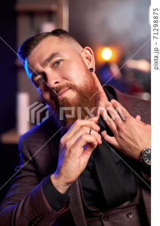 barber in a barber shop shaves his beard himself with scissors 71298875