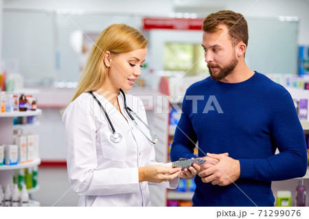 caucasian friendly pharmacist has a nice conversation with a client, helps to find a medication 71299076