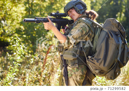 sportive woman soldier shooting with rifle machine gun in the forest 71299582