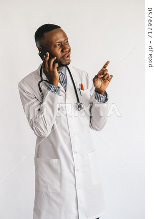 Closeup picture of young African American doctor standing in white uniform against white background Closeup picture of young African American doctor standing in white uniform against white background 71299750