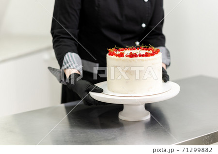 pastry chef preparing a cake with red currants 71299882