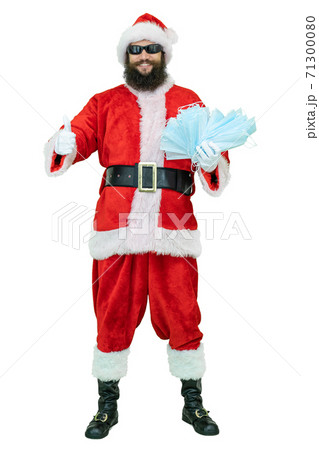 Santa Claus holds covid medical mask. Young arabic Santa shows thumb finger up 71300080