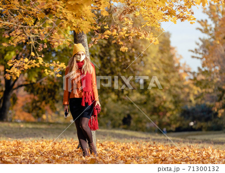 Worried woman checking her phone wearing mask in fall 71300132